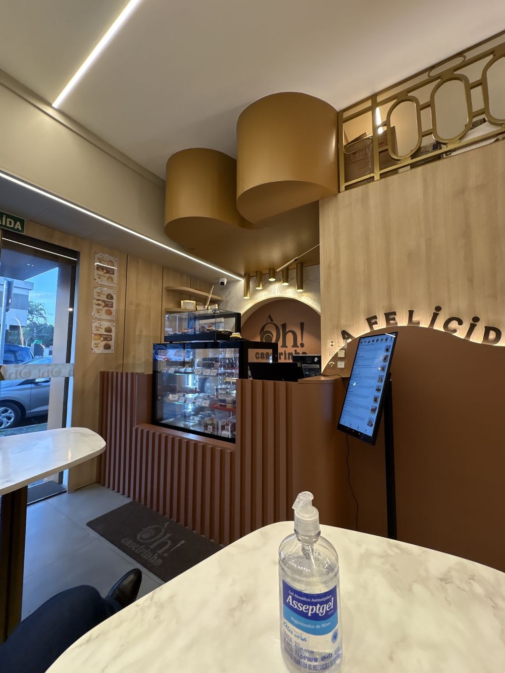 Interior com balcão de madeira, vitrine e mesa de mármore