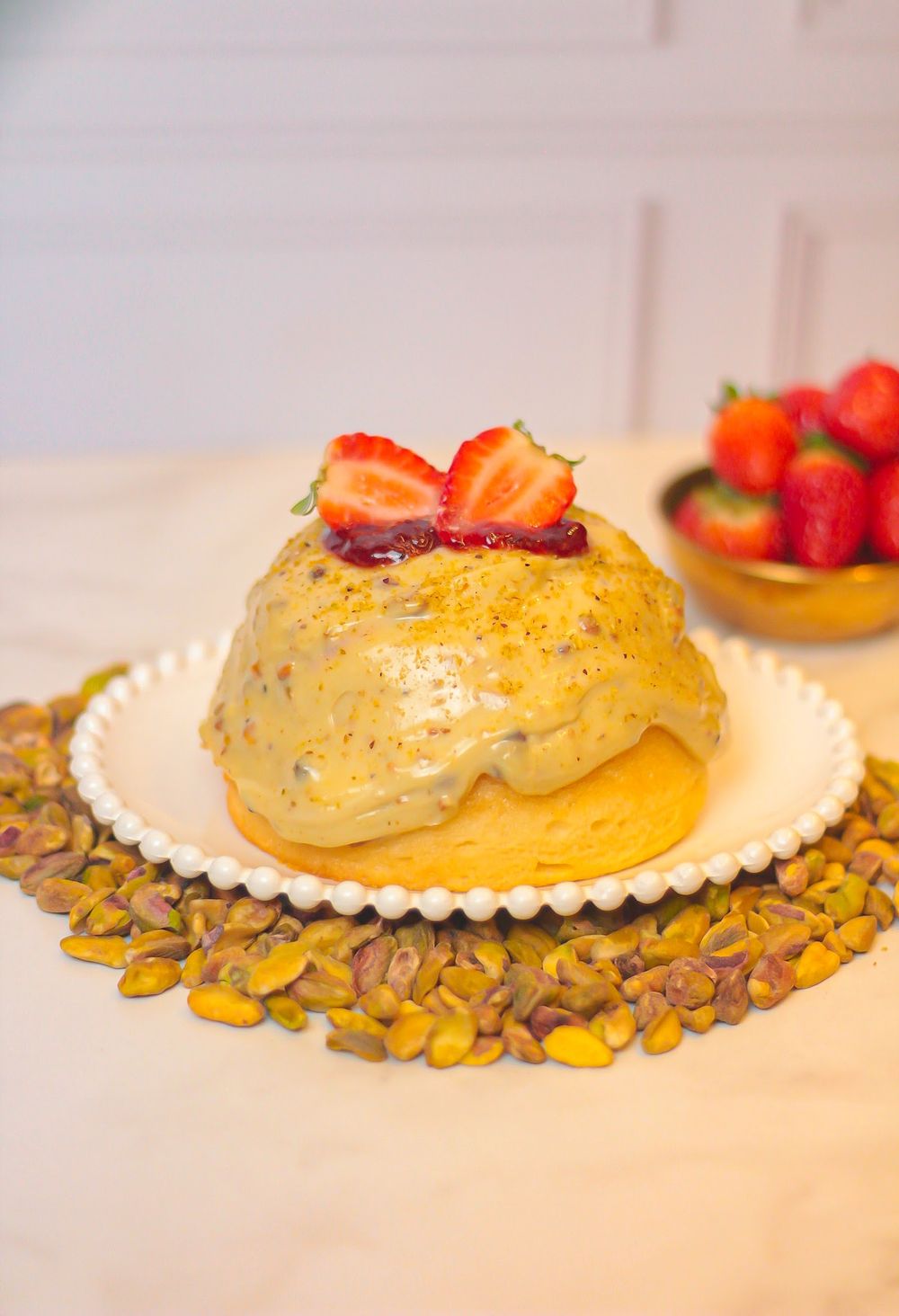 Doce com pistache e morango sobre prato branco
